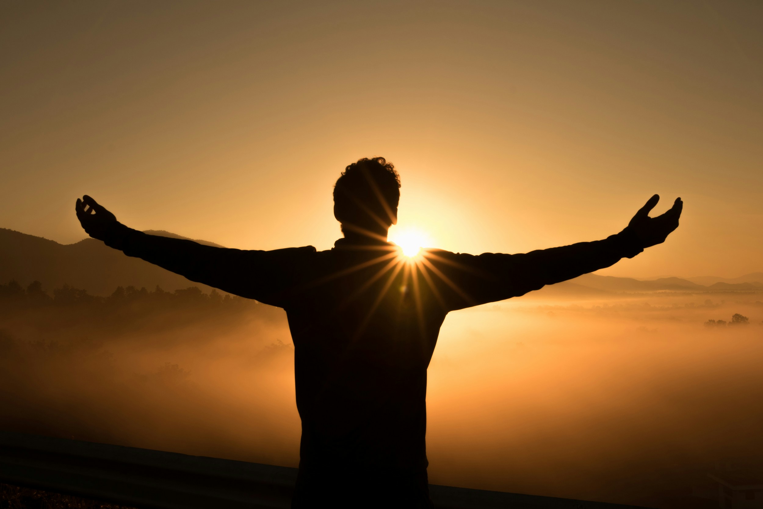 Un homme les bras ouverts face au soleil